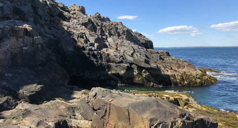 A rocky shore meets a blue ocean. 